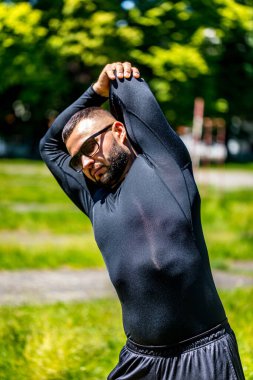 Parkta esneme hareketleri yapan bir adamın spor aktivitesi. Bir sporcunun sağlıklı alışkanlıkları..