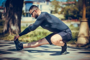 Profesyonel fitness eğitmeni. Erkek sporcu kendini eğitiyor, esneme hareketleri yapıyor. Açık hava spor konsepti.