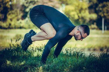 Germe ellerde ve park yeşil çimenlerin üzerinde dostum. Atlet açık havada egzersiz yapmak. Spor, yoga, pilates, fitness, sağlıklı yaşam konsepti.