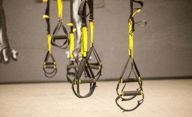 Kayışlar eğitim döngüsü ekipmanı. Gri arka planda siyah işlevsel eğitim ekipmanları. Spor aksesuarları. Sağlık için spor ve spor aletleri. Kendi ağırlık ile çalışmak için Trx fitness kayışları.