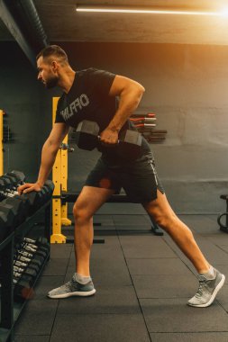 Vücut geliştiren kaslı adamın spor salonunda ağırlık çalışmasını yakından takip et. Fitness veya spor konsepti.