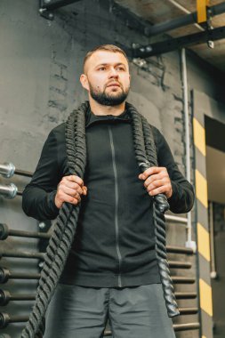 Spor salonunda savaş halatlarıyla çalışan genç bir adam. Spor fitness konseptini kapat.