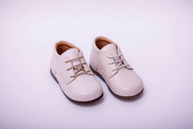 Beyaz arka planda izole edilmiş küçük beyaz deri ayakkabılar..