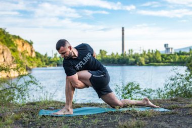 Doğada yoga yapan genç bir adam. Sağlıklı yaşam tarzı, meditasyon, yaşam tarzı konsepti. Uluslararası Yoga Günü
