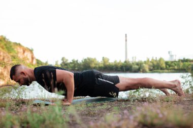 Sade, sakallı, siyah elbiseli, esneme sporu yapan, yoga yapan, spor yapan, spor yapan, spor yapan, spor yapan veya yeşil çimenlikte egzersiz yapan, esnek omurga egzersizi yapan çekici bir genç profili..