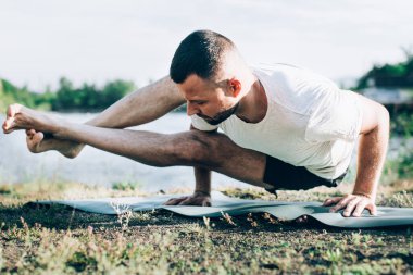 Genç bir adam güneşin altında taş ocağında yoga yapıyor. Yoga pozunda oturuyor. Denge, uyum, konsantrasyon ve rahatlama..