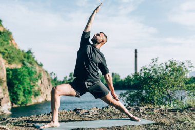 Güneşli bir günde taş ocağı gölünde yoga egzersizi yapan adam. Uluslararası Yoga Günü.