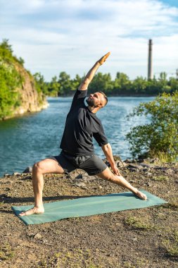 Güneşli bir günde taş ocağı gölünde yoga egzersizi yapan adam. Uluslararası Yoga Günü.