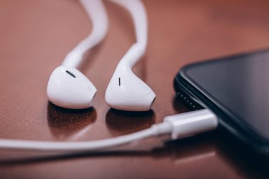 Eski rustik ahşap masa üzerinde kulaklıklı akıllı telefon, müzik ve podcast konsepti, metin için kopyalama alanı, seçici odak resmi.