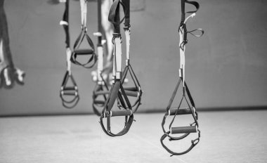 Kayışlar eğitim döngüsü ekipmanı. Gri arka planda siyah işlevsel eğitim ekipmanları. Spor aksesuarları. Sağlık için spor ve spor aletleri. Kendi ağırlık ile çalışmak için Trx fitness kayışları.