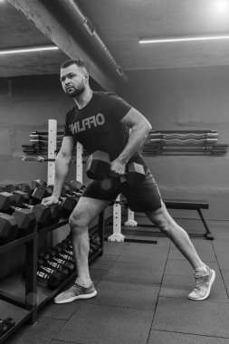 Vücut geliştiren kaslı adamın spor salonunda ağırlık çalışmasını yakından takip et. Fitness veya spor konsepti.