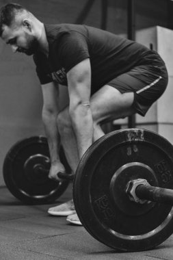 Spor salonunda halterle çalışan kaslı bir adamın portresi. Fitness spor konsepti.