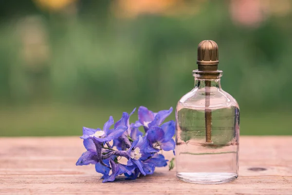 Perfume bottle with flowers on light background. Perfume bottle with tag and small flowers on the table.