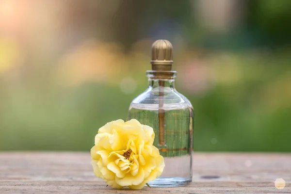 Perfume bottle with flowers on light background. Perfume bottle with tag and small flowers on the table.