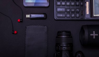 Dijital kamerası, hesap makinesi, USB sürücüsü ve fotokopi alanı olan siyah masa arkaplanı ile en iyi çalışma alanı fotoğrafçısı. Modern siyah aksesuarlar, minimal tasarım araçları.