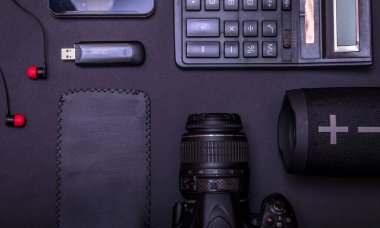 Dijital kamerası, hesap makinesi, USB sürücüsü ve fotokopi alanı olan siyah masa arkaplanı ile en iyi çalışma alanı fotoğrafçısı. Modern siyah aksesuarlar, minimal tasarım araçları.
