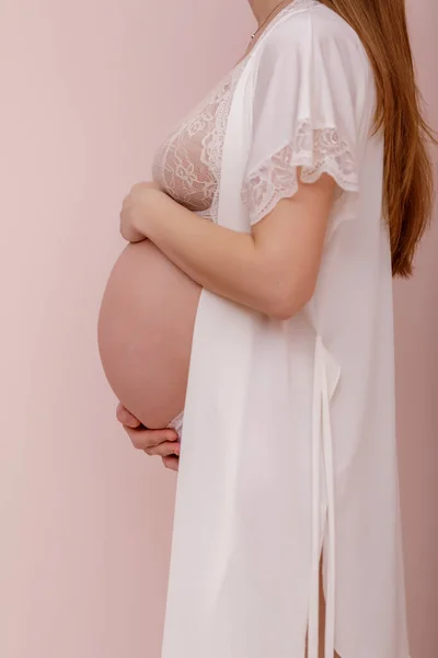 パステルピンクの背景で手で認識できない妊娠中の女性のクローズアップ 高解像度画像 — ストック写真