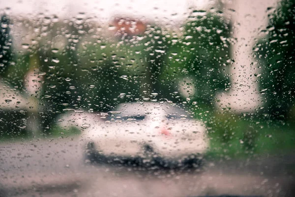 Raindrops on a car glass against a blurred background with a view of the city and the lights of cars. High resulotion image.