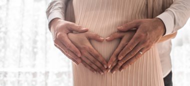 Hamile kadınlar kollarını karın çevresine kalp şeklinde sararlar. Aile kavramı. Yüksek resulotion resmi.