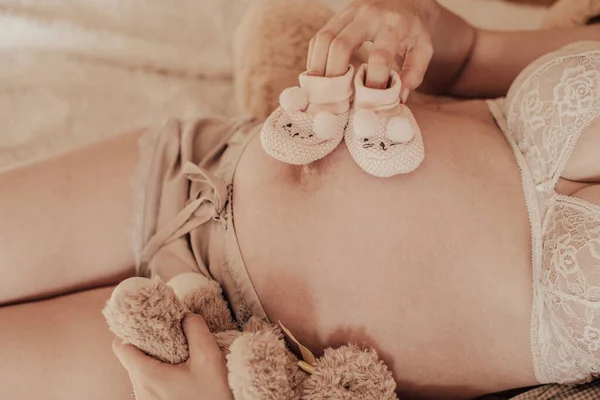妊娠中の幸せな女性は彼女の手で赤ん坊の靴を保持する ママは赤ちゃんを待ってる 妊娠中の腹 妊娠中 家族の概念 高解像度画像 — ストック写真