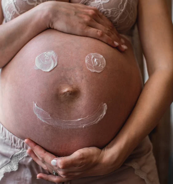 Painted happy smiley face on the belly of pregnant woman. High resulotion image.