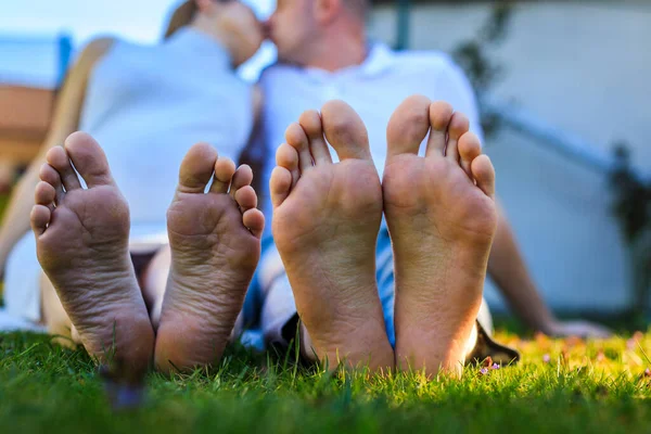 Romantic young couple kissing in the garden. Family feet in focus. Feet of a young couple lying on grass at the park. High resulotion image.