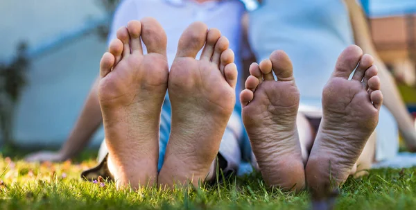 Romantic young couple kissing in the garden. Family feet in focus. Feet of a young couple lying on grass at the park. High resulotion image.