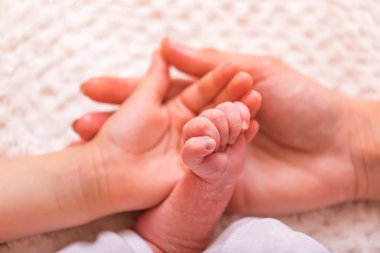 Yumuşak bebek elleri. Yeni doğmuş bebek eli, annesinin ve kız kardeşinin avucunun içinde. Battaniyenin üzerinde bir annenin elinde çocuk eli. Yeni aile kavramı, bebek bakımı ve korunması. Pullu cilt.