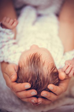Sevgi dolu anne, yeni doğmuş bebeğini evde taşıyor. Mutlu annenin uyuyan bebeği elinde tutarken çekilmiş yakın plan fotoğrafı. Anne küçük kızını kucaklıyor..