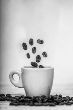 Kahve çekirdekleri beyaz fincana düşüyor. Yüksek hızlı atış. Kavrulmuş kahve çekirdekleri kahve fincanına dökülüyor. Beyaz arka plan, taze enerji duvar kağıdı konsepti..