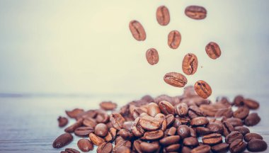 Kahverengi kahve çekirdekleri beyaz arka planda düşüp uçuyor. Bir kahve çekirdeğine odaklanmış kahve çekirdeği..