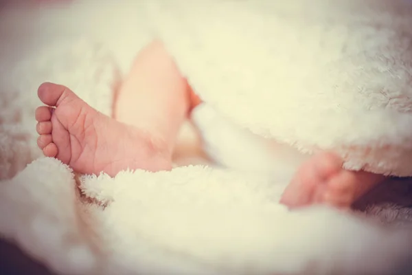 新生児の足 ベッドの上の穏やかな朝の光の中で甘い赤ちゃん 暖かい白い毛布の中でかわいい新生児の裸の足 子供の頃 小さな赤ん坊の女の子や男の子の小さな裸の足 — ストック写真