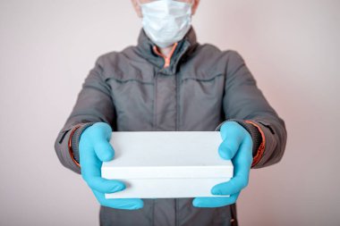 Kurye, tek kullanımlık eldivenlerde karton kutular tutuyor. Coronavirus covid-19 ncov 'un karantina süresi boyunca temassız teslimat. Evde kal ve internetten alışveriş yap.