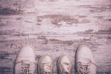 Babacığın botları ve bebek ayakkabıları, eski püskü ahşap arka planda, Babalar Günü konsepti. Klasik renk efekti. Yüksek resulotion resmi.
