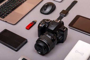 Dijital kamera, harici sabit diski olan usb ya da gri kağıt arka planda profesyonel fotoğrafçının bataryası ve ekipmanı. Tasarımcı iş yeri konsepti. Yüksek resulotion resmi.