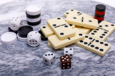 Oyunların karışımı kapanıyor. Eski bir mermer masa arka planında çeşitli masa oyunları zarları ve dominolar. Yüksek resulotion resmi.