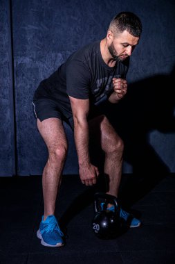 Vücut geliştiren adam ağırlık çalışması yapıyor. Ağır kettlebell kaldırarak. Sakallı genç bir sporcu kettlebell salıncakları yapıyor. Vücut geliştirici spor salonunda kettlebell ile kaldırıyor. Yüksek resulotion resmi.