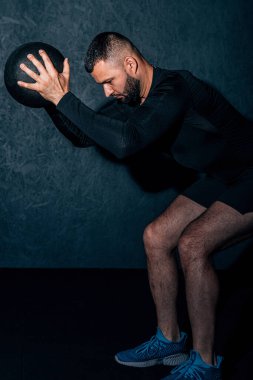 Adam gri arka planda büyü topuyla çalışıyor. Sakallı yakışıklı genç kaslı sporcu spor salonunda bir tıp topuyla çalışıyor. Yüksek resulotion resmi.