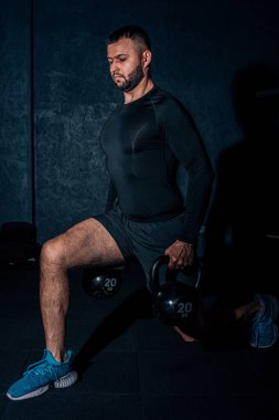 Atletik beyaz adam, çan kaldırırken çömeliyor. Genç kaslı adam spor salonunda kettlebell ile egzersiz yapıyor. Ağırlık kaldırma egzersizi. Spor, spor konsepti. Yüksek resulotion resmi.