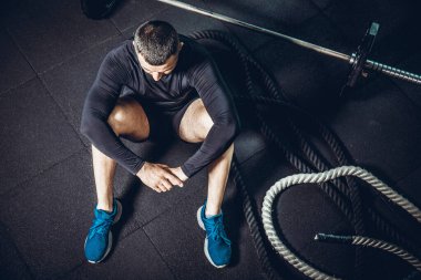 Eğitimden sonra dinleniyorum. Spor salonundaki paspasın üzerinde oturan sakallı genç adamın bakışları. Yüksek resulotion resmi.