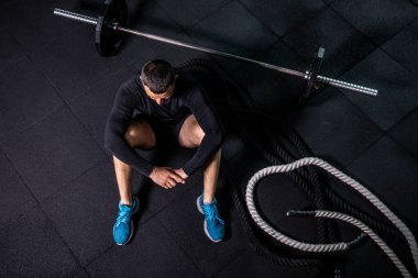 Eğitimden sonra dinleniyorum. Spor salonundaki paspasın üzerinde oturan sakallı genç adamın bakışları. Yüksek resulotion resmi.