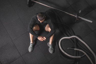 Eğitimden sonra dinleniyorum. Spor salonundaki paspasın üzerinde oturan sakallı genç adamın bakışları. Yüksek resulotion resmi.