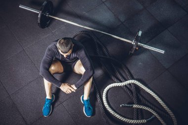 Eğitimden sonra dinleniyorum. Spor salonundaki paspasın üzerinde oturan sakallı genç adamın bakışları. Yüksek resulotion resmi.