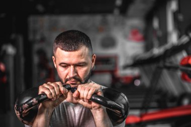 Sakallı jimnastikçi ağırlık antrenmanı yapıyor. Ağır kettlebell kaldırarak. Yong atleti kettlebell salıncakları yapıyor. Kettlebell ile vücut geliştirici kaldırma. Yüksek resulotion resmi.