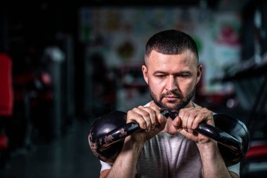 Sakallı jimnastikçi ağırlık antrenmanı yapıyor. Ağır kettlebell kaldırarak. Yong atleti kettlebell salıncakları yapıyor. Kettlebell ile vücut geliştirici kaldırma. Yüksek resulotion resmi.