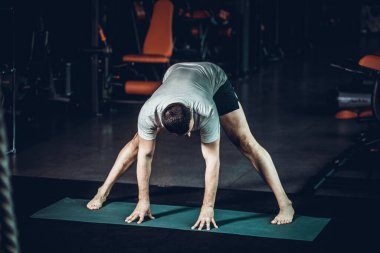 Sportif genç adam yoga yapıyor, esneme egzersizleri yapıyor, üçgen pozlar veriyor esnek omurga için utthita trikonasana asana ve spor salonundaki stresi azaltıyor. Yüksek resulotion resmi.