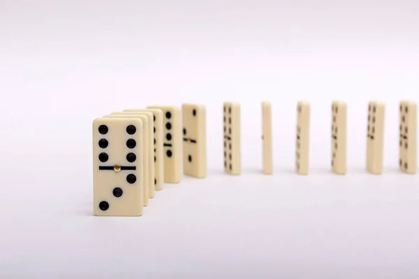 Domino\'s effect composition of a multiple domino bones placed in a row in white background. High resulotion image.