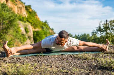 Genç fitness adamı taş ocağı gölünde yoga egzersizi yapıyor. Sakallı yakışıklı genç adam yoga egzersizi yapıyor..