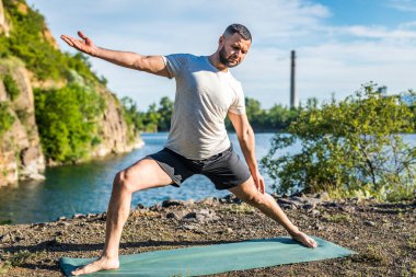Elleri ve bacakları eşe uzatan bir adam. Sakallı adam taş ocağında ve dağlarda yoga yapıyor..