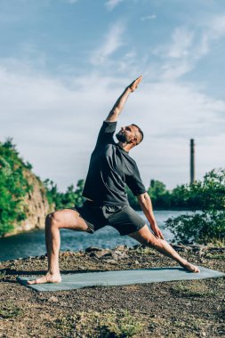 Güneşli bir günde taş ocağı gölünde yoga egzersizi yapan adam. Uluslararası Yoga Günü.